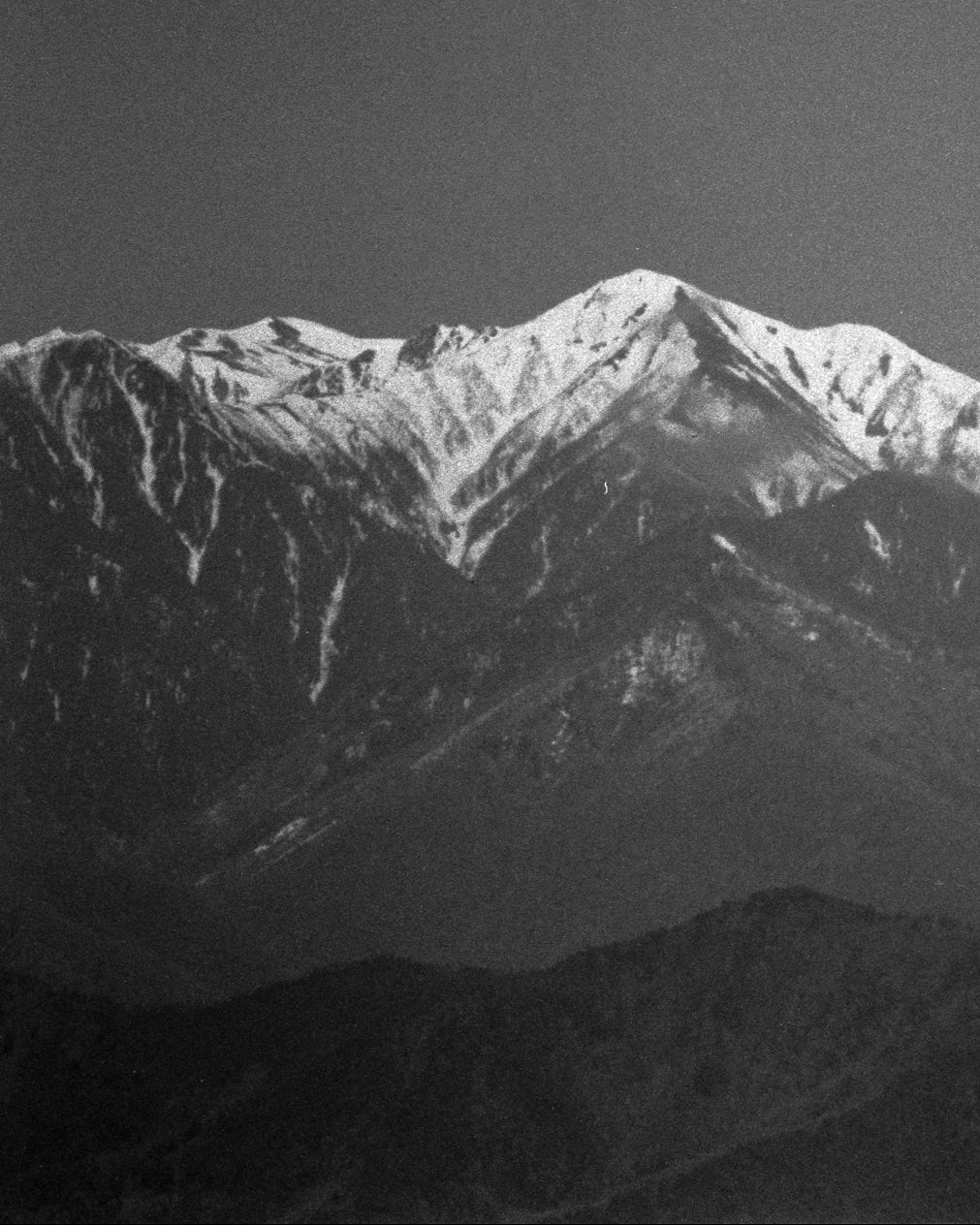 Black and white photograph of snow-capped mountains.